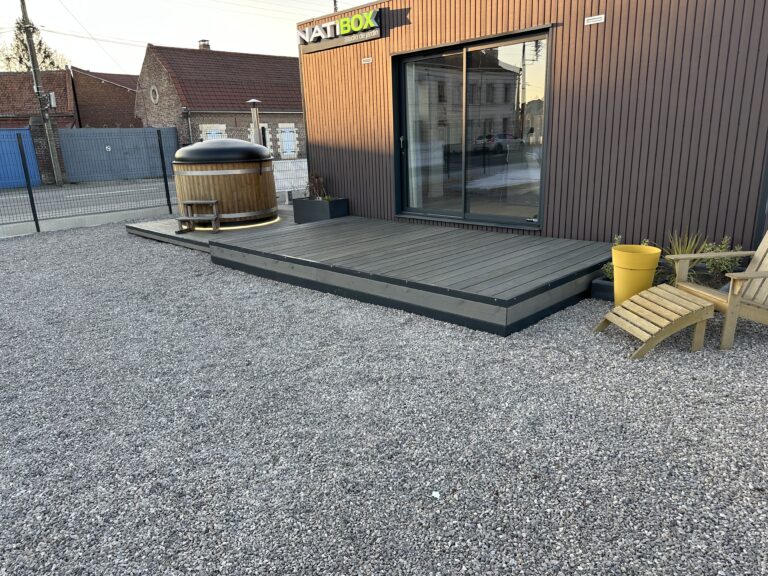 Terrasse modulaire en bois devant une Natibox avec fauteuil et bain nordique sur sol gravillonné