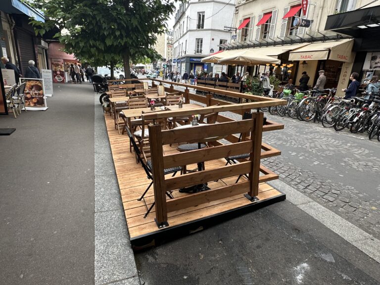 Terrasse modulaire bois installée sur l’espace public rue des Abbesses à Paris, avec rambardes et mobilier en place