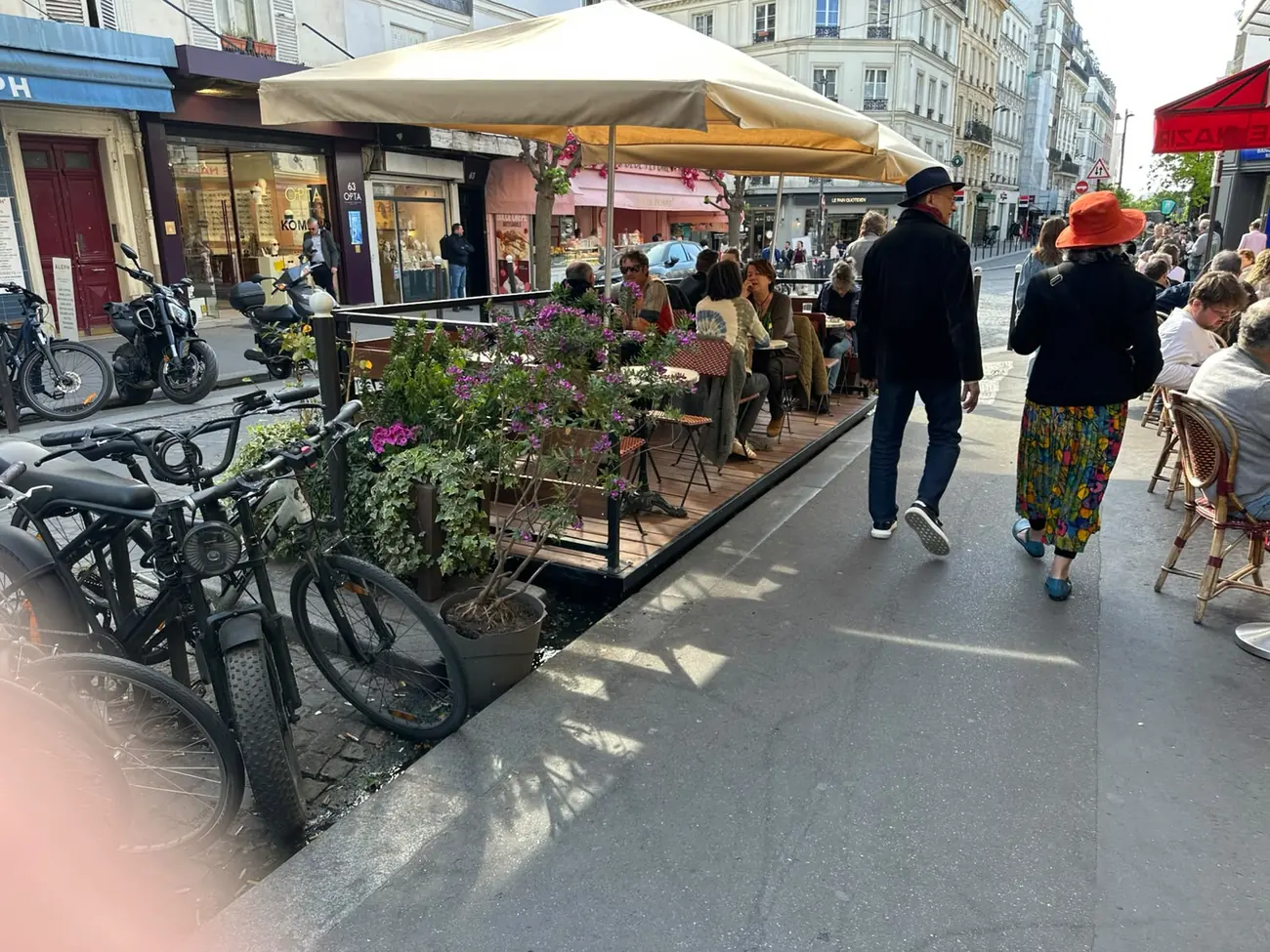 Après : terrasse de restaurant fleurie et occupée dans une rue passante