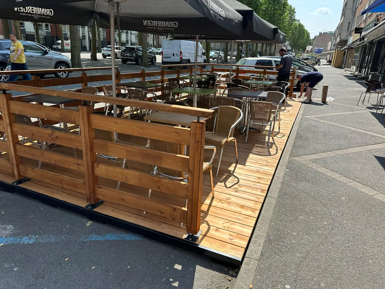 Terrasse de brasserie sous parasols sur une place arborée