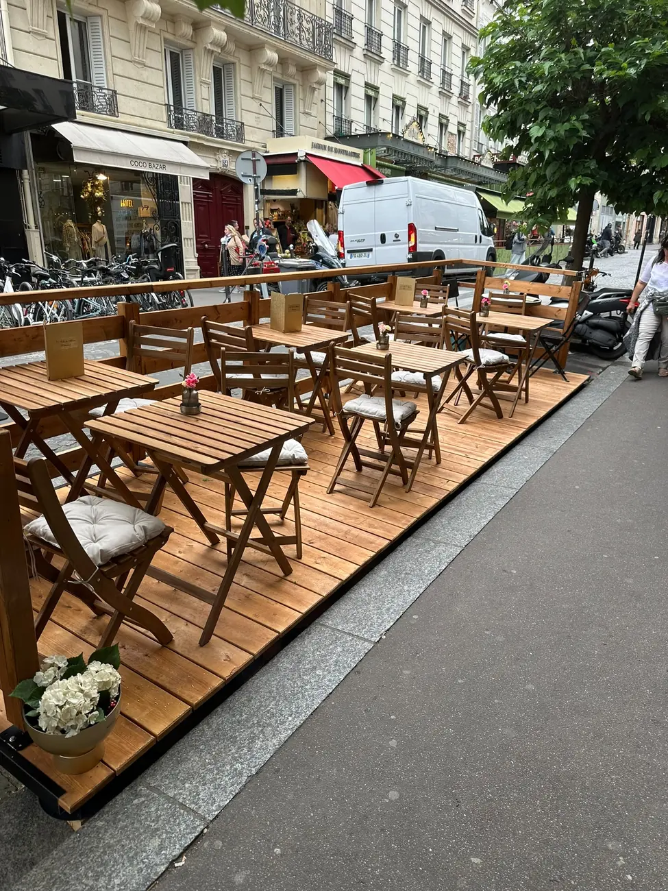 Terrasse de café de plain-pied sur un trottoir en pente à Paris